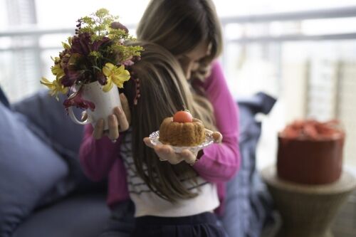 Mother embracing daughter with desserts in hand.